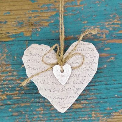 A romantic, rustic-inspired greetings card featuring two stone hearts tied up with a string on a shabby chic blue wood background